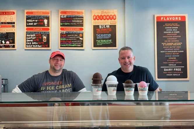 interior of an ice cream shop counter with two males behind the counter smiling